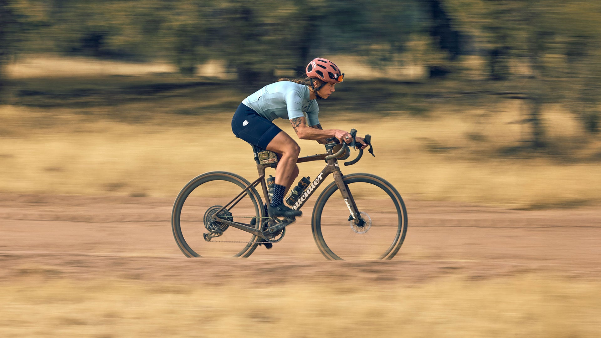 Cyclist riding gravel road on drop bar bike