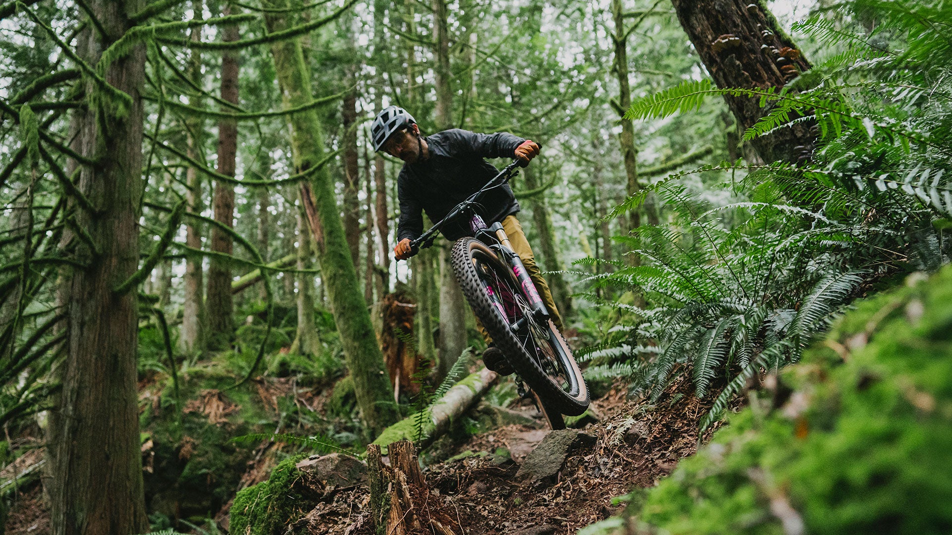 Mountain biker descending rocky and loamy forest trail